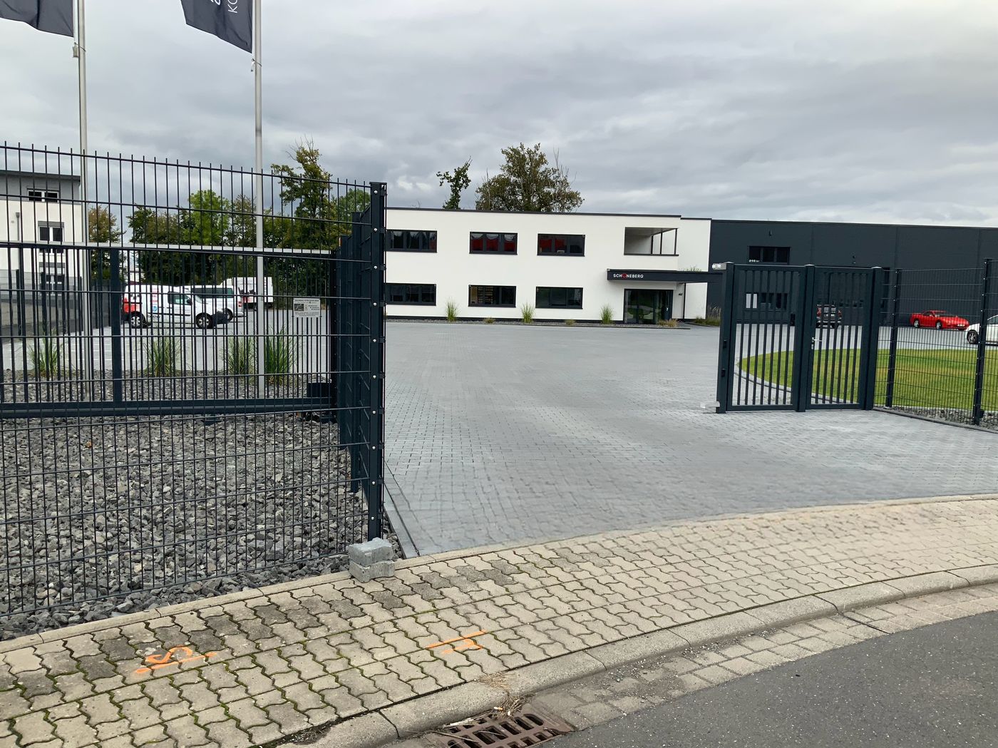 Toranlage mit Fahnenmasten vor Firmengebäude